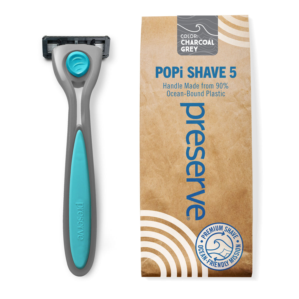 A razor with a charcoal grey POPi Shave 5 razor next to its packaging box. The box is brown kraft-paper style with blue text reading 'preserve' and 'POPI SHAVE 5'.